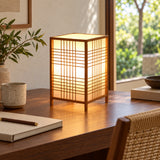 Luminária de mesa Shoji sobre mesa de madeira em escritório Japandi com luz natural.