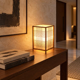 Luminária de mesa Shoji acesa sobre aparador de madeira em hall de entrada contemporâneo.