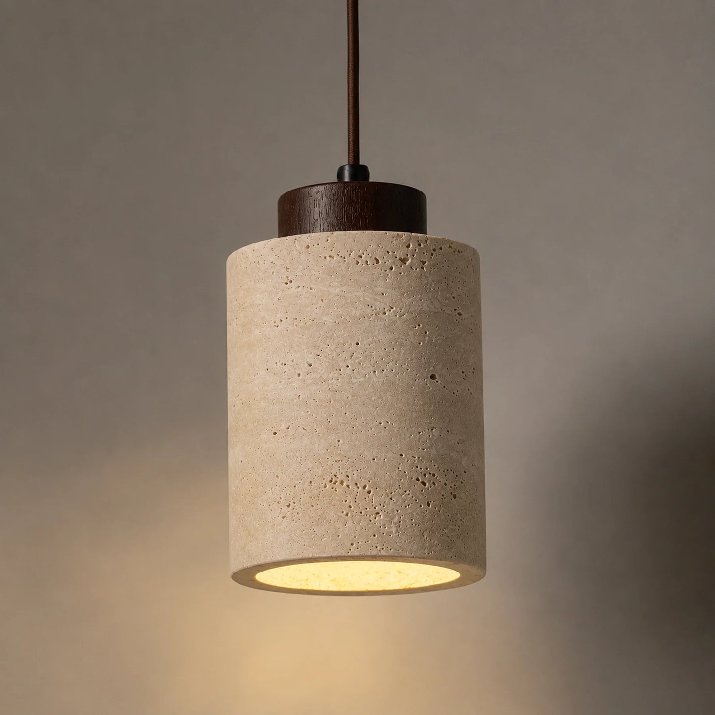 Luminária pendente em travertino acesa com iluminação aconchegante